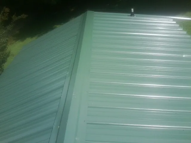 New green metal panels meeting at the ridge of a roof — Flat Roof Repair work by our crew in Royal Oak
